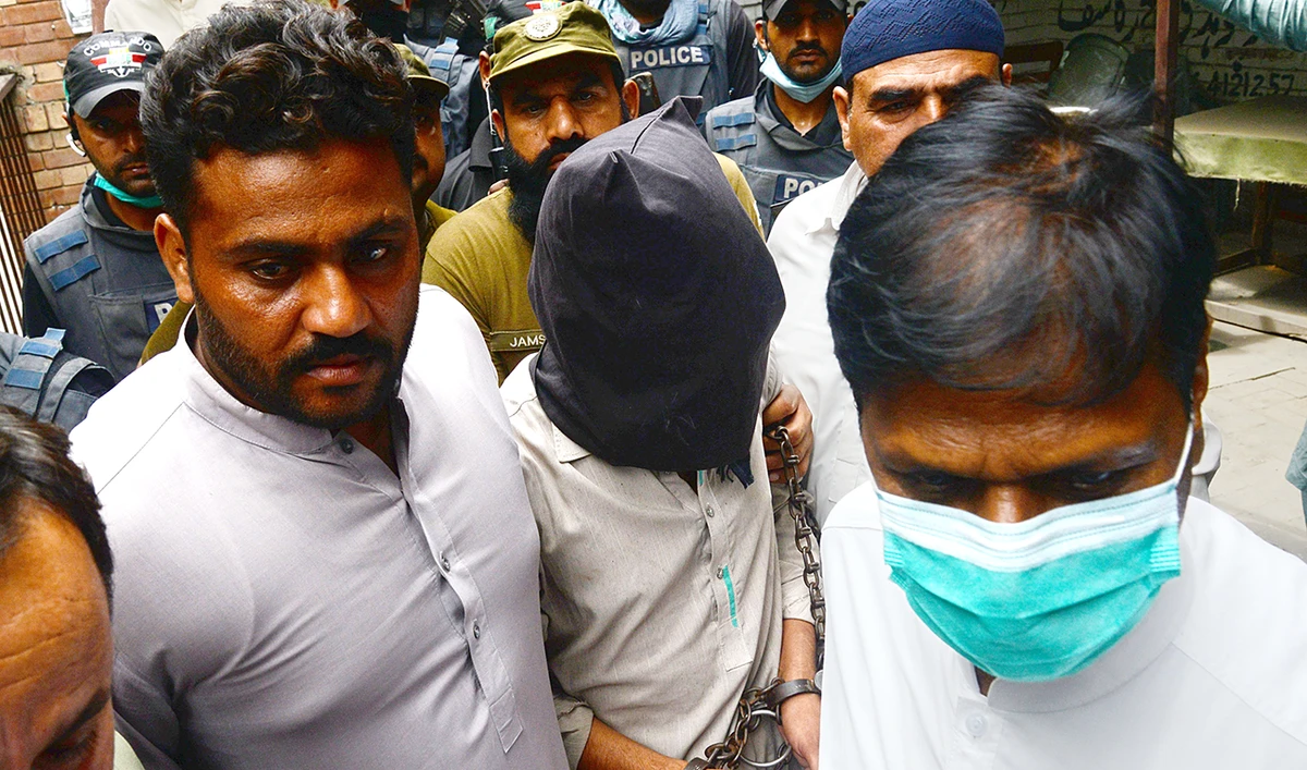 Policemen escort Shafqat Ali (face covered), one of two suspects in the gang rape case, as they leave from a local court in Lahore on Tuesday. (AFP)