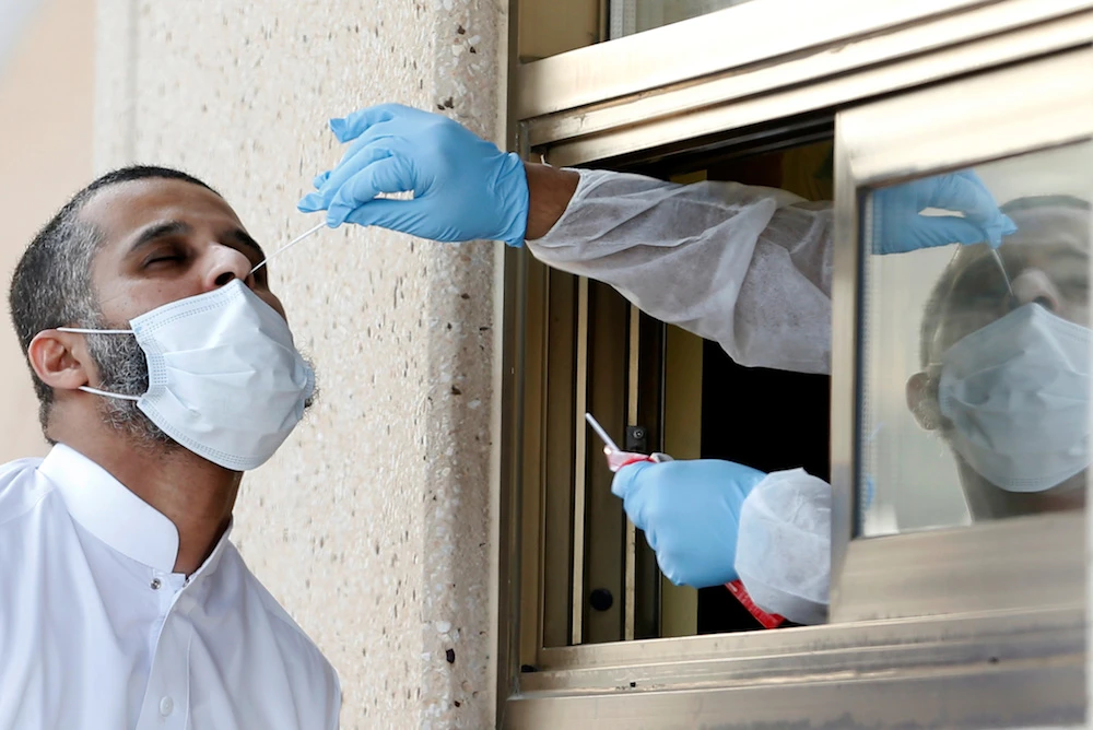A Saudi national traveling into Bahrain gets a nose swab at an immigration checkpoint on the King Fahd Causeway that reopened after coronavirus disease (COVID-19) restrictions were eased, at the Bahrain-Saudi border, Bahrain, Sept. 15, 2020. (Reuters)