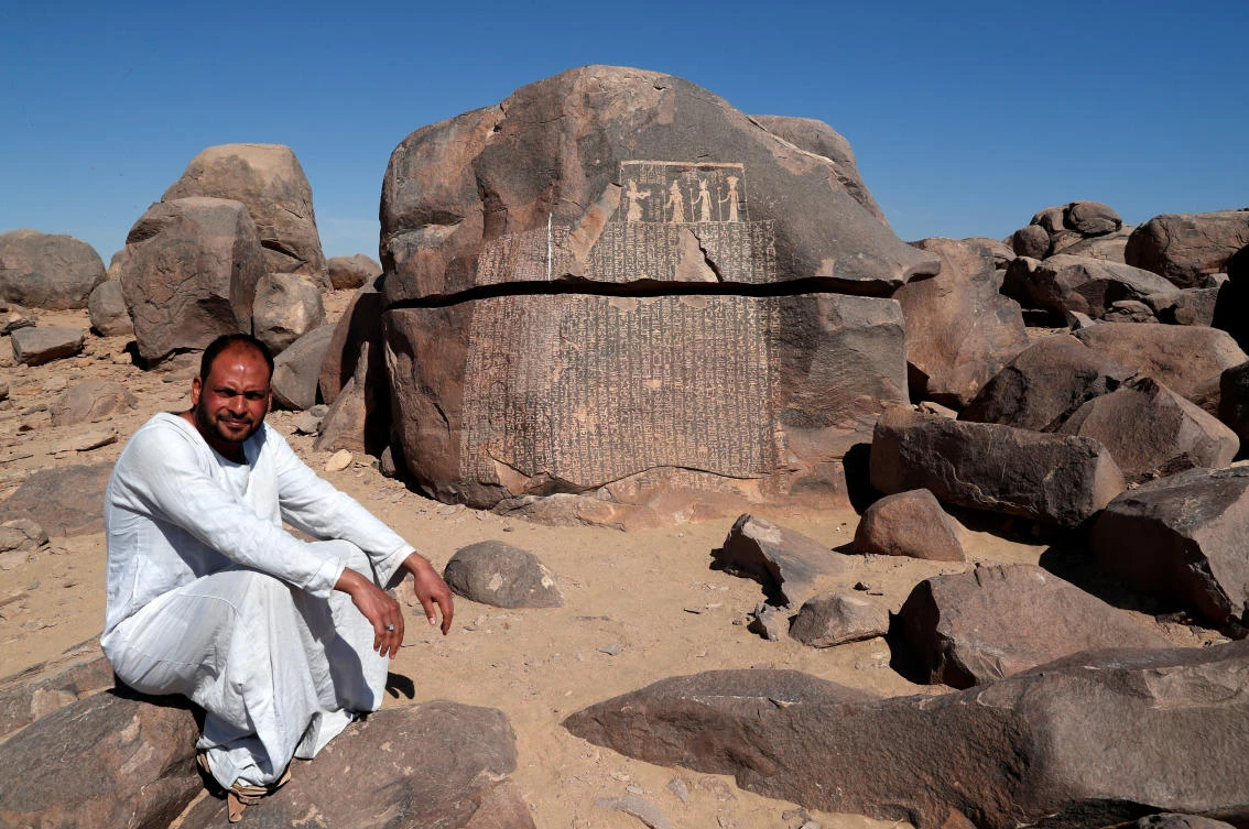 Ayman Hussien, a guard of Famine Stela, or "Rock of Starvation", sits near the rock, initially attributed to the reign of King Djoser (Third Dynasty), during a shortage of the Nile flood that led to a seven-year drought and famine, on the Nile?s Sehel Island at Aswan, Egypt February 21, 2020. Picture taken February 21, 2020. (Reuters)