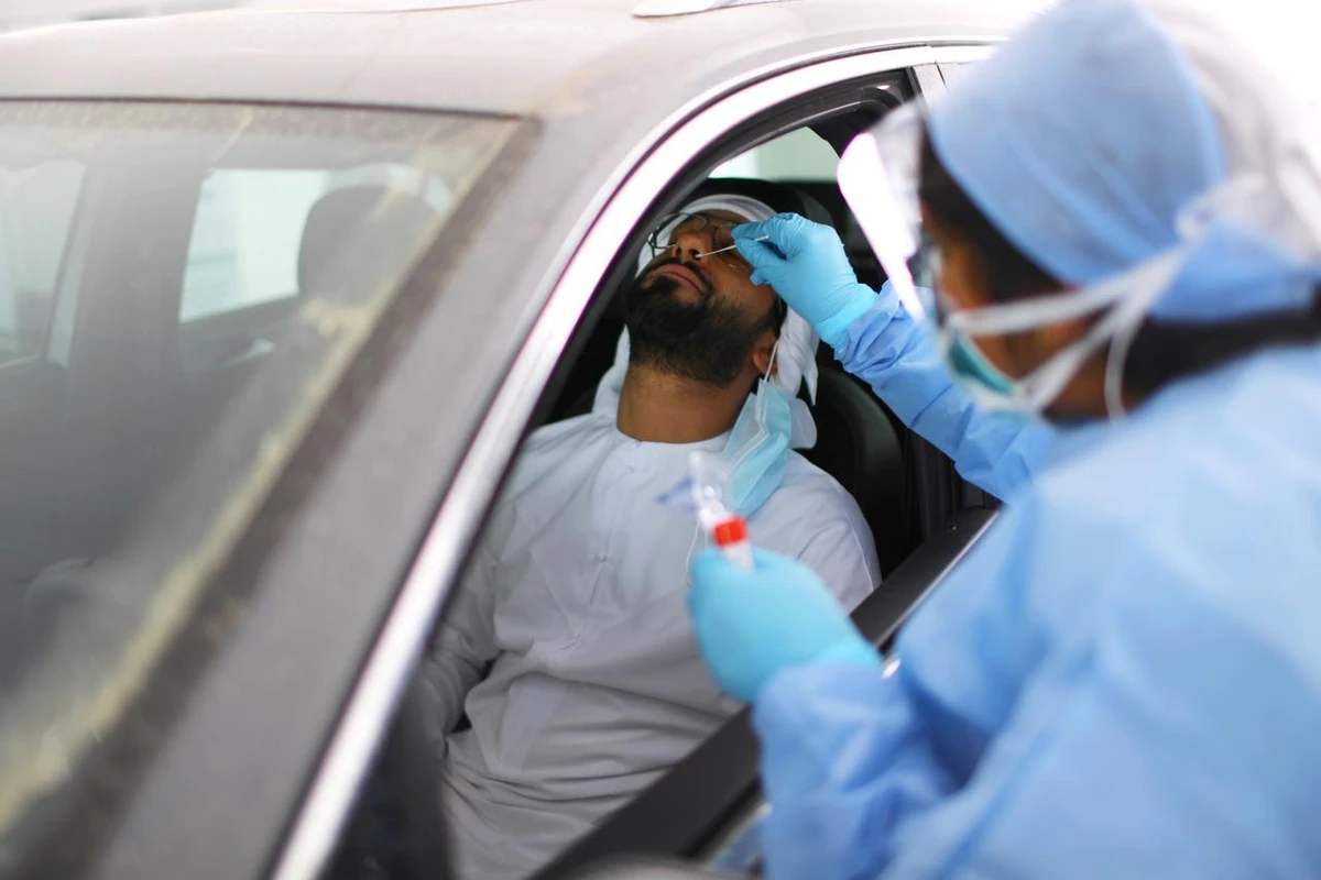A member of medical staff wearing a protective face mask and gloves takes a swab from a man during drive-thru coronavirus disease testing (COVID-19) at a screening center in Abu Dhabi, UAE. (File/Reuters)