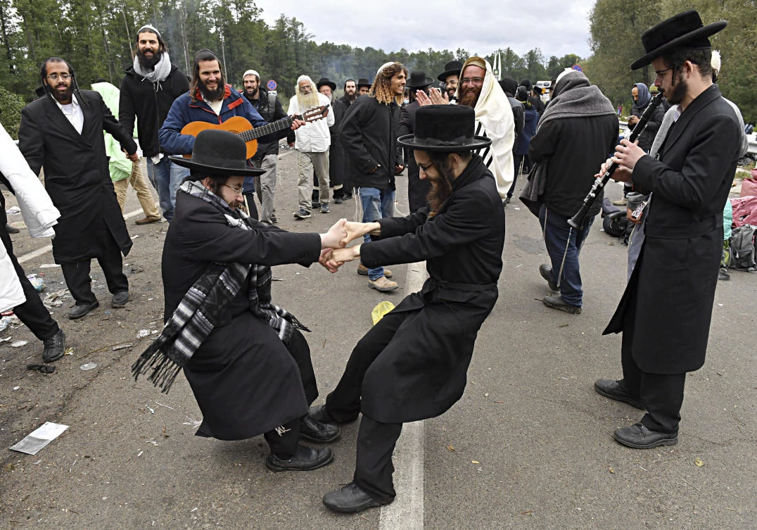 Hasidic Jewish pilgrims dance as they gather in front of Ukrainian border guards at a checkpoint near Novaya Guta, Belarus, Friday, Sept. 18, 2020. (AP Photo)