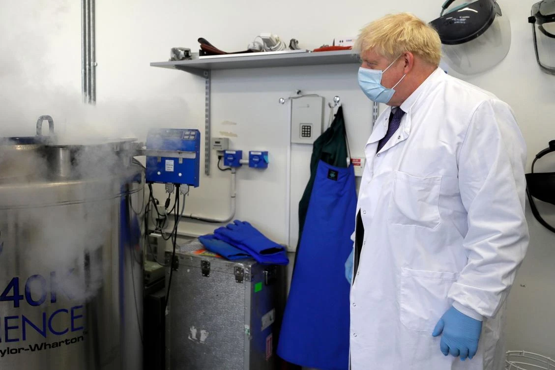 Boris Johnson looks on after he is shown samples stored in liquid nitrogen, during a visit to the Jenner Institute in Oxford, central England, on September 18, 2020. (AFP)