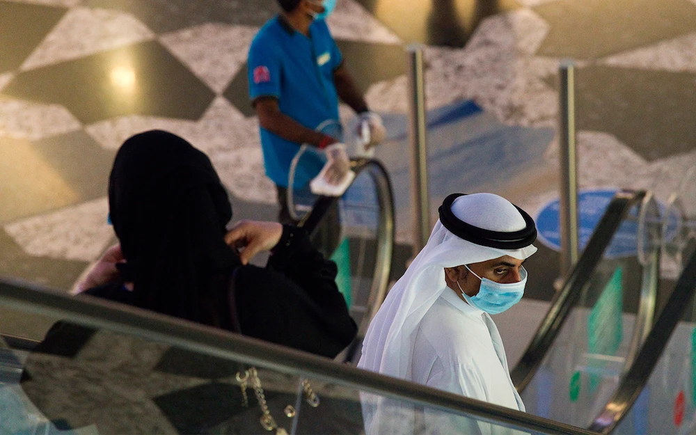 An Emirati man and woman ride an escalator at Mall of the Emirates in Dubai, UAE, as the country loosens its coronavirus restrictions. (File/AP)