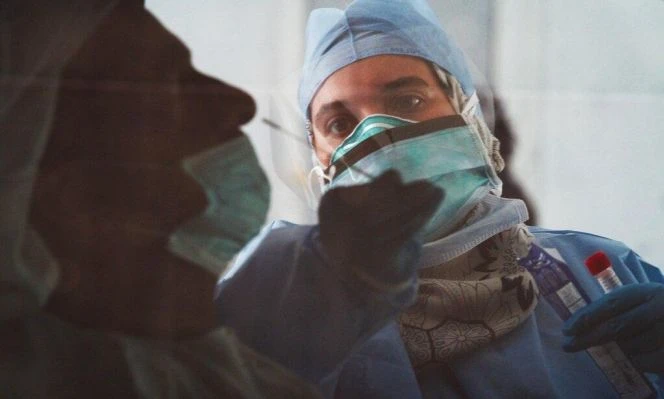 In this image taken through a tinted car window, a technician takes a nasal swab for a new coronavirus detection test at a drive-thru testing facility in Abu Dhabi. (AP)