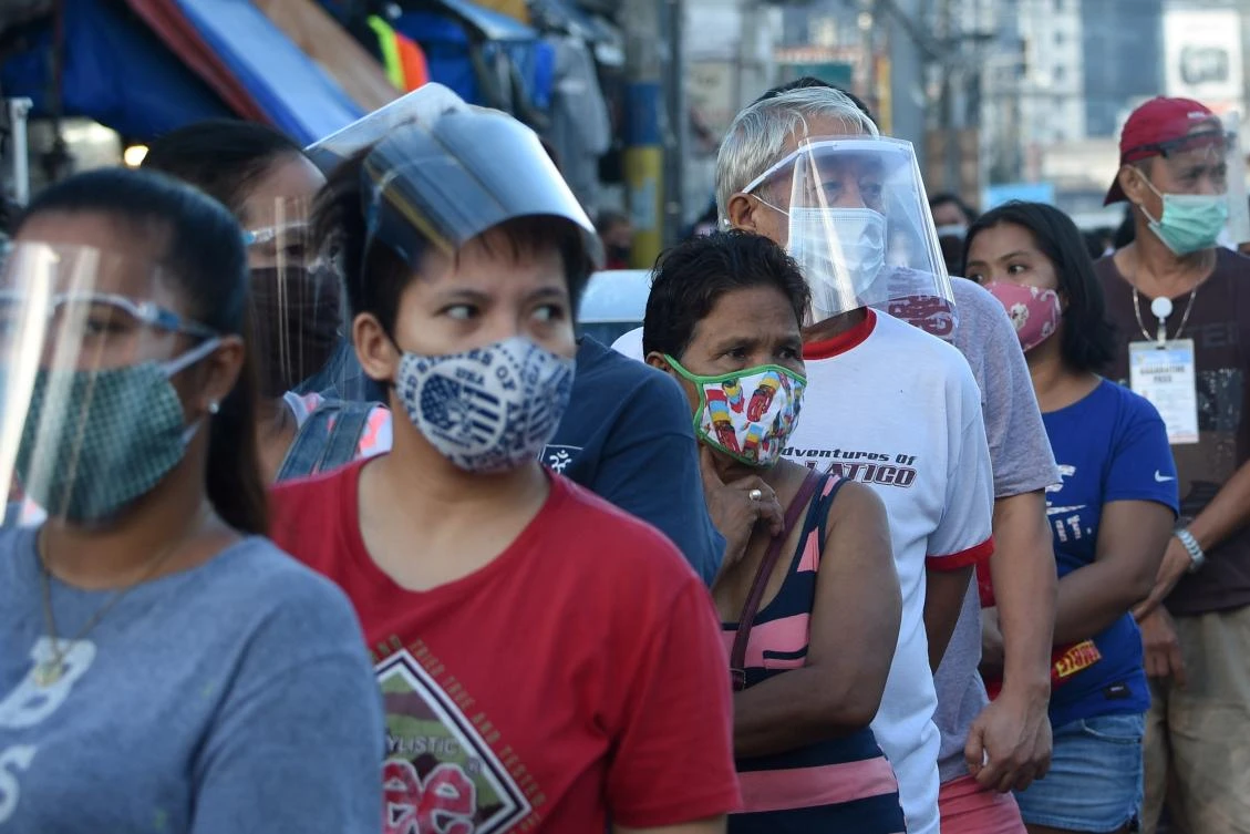 In this photo taken on September 19, 2020, people wearing face shields queue up at a public market in Manila. Many face the new normal in the Philippines, where it is now compulsory to wear both face masks and plastic shields in indoor public spaces and on public transport to curb the spread of the COVID-19 coronavirus. (AFP)
