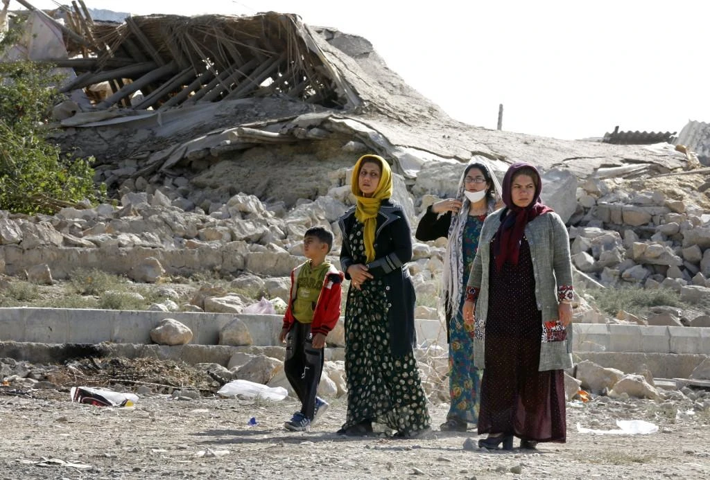 A file photo shows Iranians walking past the rubble of buildings. (File/AFP)