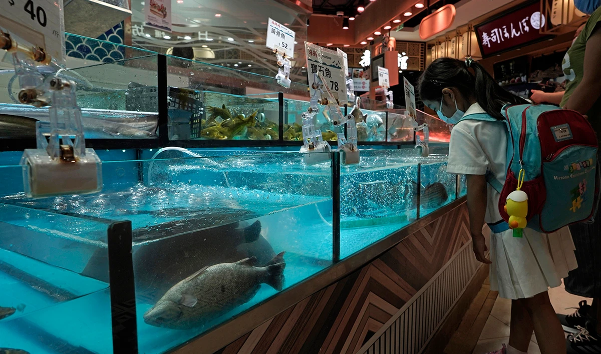 A girl stands next to the fish from MoVertical Farm at a supermarket in Hong Kong Thursday, Sept. 24, 2020. Operating on a rented 1,000 square meter patch of wasteland in Hong Kong's rural Yuen Long, Arthur Lee's MoVertical Farm utilizes around 30 of the decommissioned containers, to raise red water cress and other local vegetables hydroponically, which eliminates the need for soil. (AP)