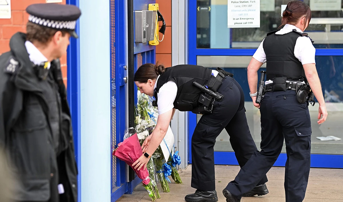 Police officers leave floral tributes outside the Croydon Custody Centre in south London on September 25, 2020, following the shooting of a British police officer by a 23-year-old man being detained at the centre. (AFP)