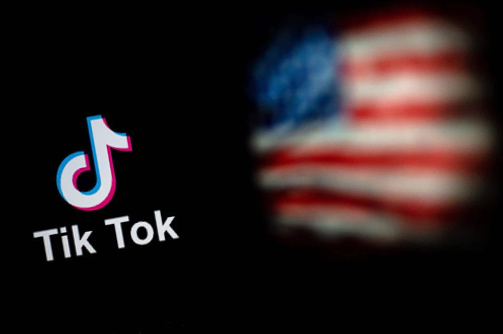 This file photo illustration taken on Sept. 14, 2020 shows the logo of the social network application TikTok and a US flag on the screens of two laptops in Beijing. (AFP / NICOLAS ASFOURI)