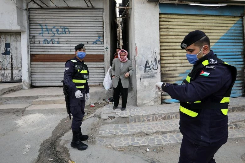 Jordanian police officers stand guard as a man waits to get bread in a closed-down part of Al-Nasr area, amid the coronavirus disease (COVID-19) outbreak, in Amman, Jordan, April 15, 2020. (Reuters)