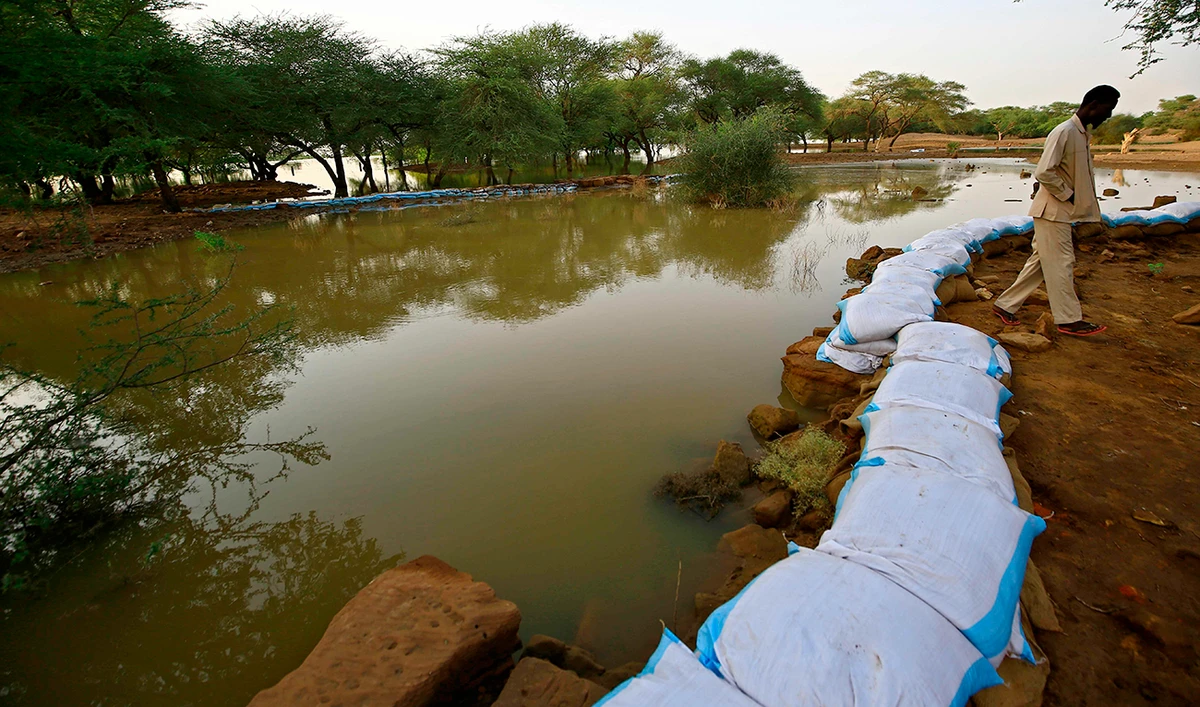 A worker with the Sudanese antiquities authority lines a stone wall with sandbags to mitigate flood water damage to a structure. (AFP)