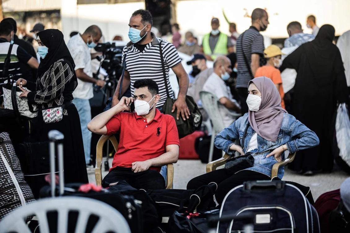 Palestinians, mask-clad due to the COVID-19 coronavirus pandemic, wait to cross to the Egyptian side of Rafah border crossing in the southern Gaza Strip on September 27, 2020. (AFP)