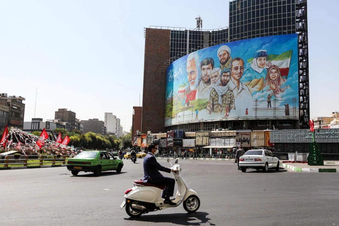 A mask-clad man (COVID-19 coronavirus pandemic precaution) rides a scooter along Valiasr Square in Iran's capital Tehran on September 27, 2020, past a giant billboard depicting the faces of slain Iranian general Qasem Soleimani and Iraqi paramilitary chief Abu Mahdi al-Muhandis along with other medical workers with text in Persian reading "we are a nation of martyrs". (AFP)
