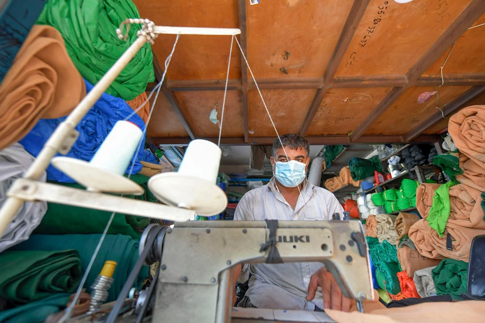 A man wearing a protective mask amid the COVID-19 pandemic sews fabric at his shop in Dubai in the United Arab Emirates, on September 10, 2020. (AFP/File Photo)