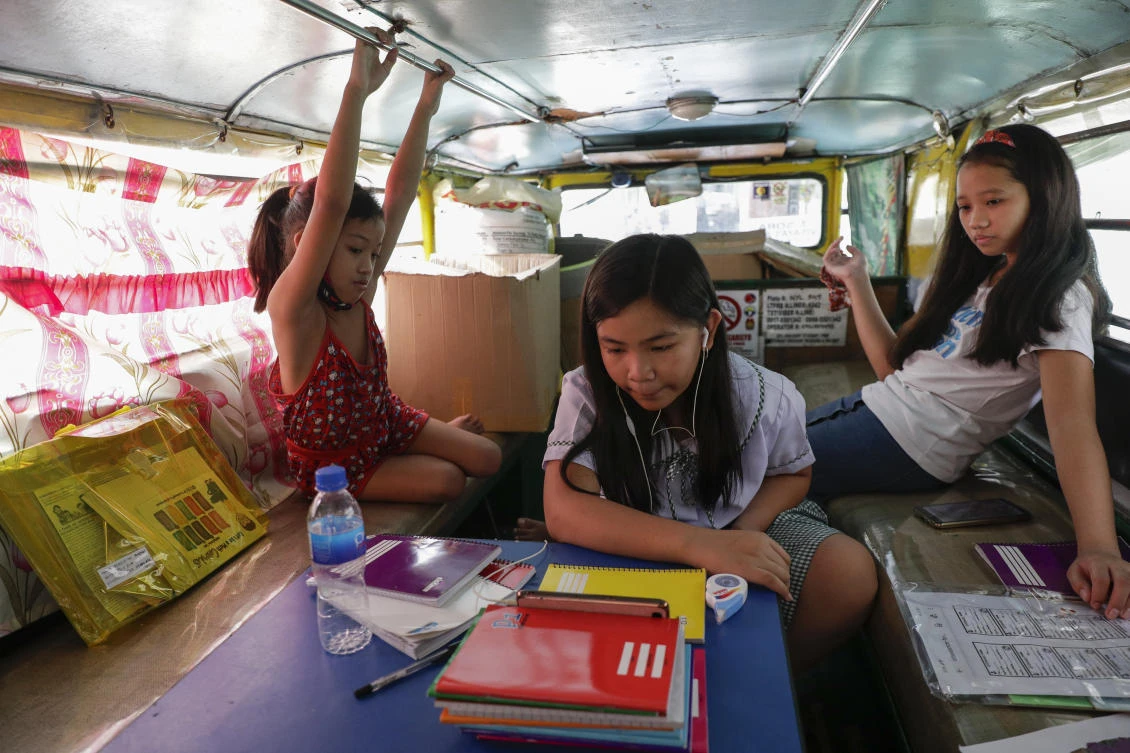 Grade school student Bhea Joy Roxas, center, uses a smartphone for online classes while her friends observe inside a passenger jeepney in Quezon City on Monday, Oct. 5, 2020. (AP)