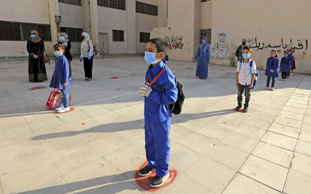 Jordanian students, wearing protective masks, wait in line on the first day of school on Sept. 1, 2020. (AFP)