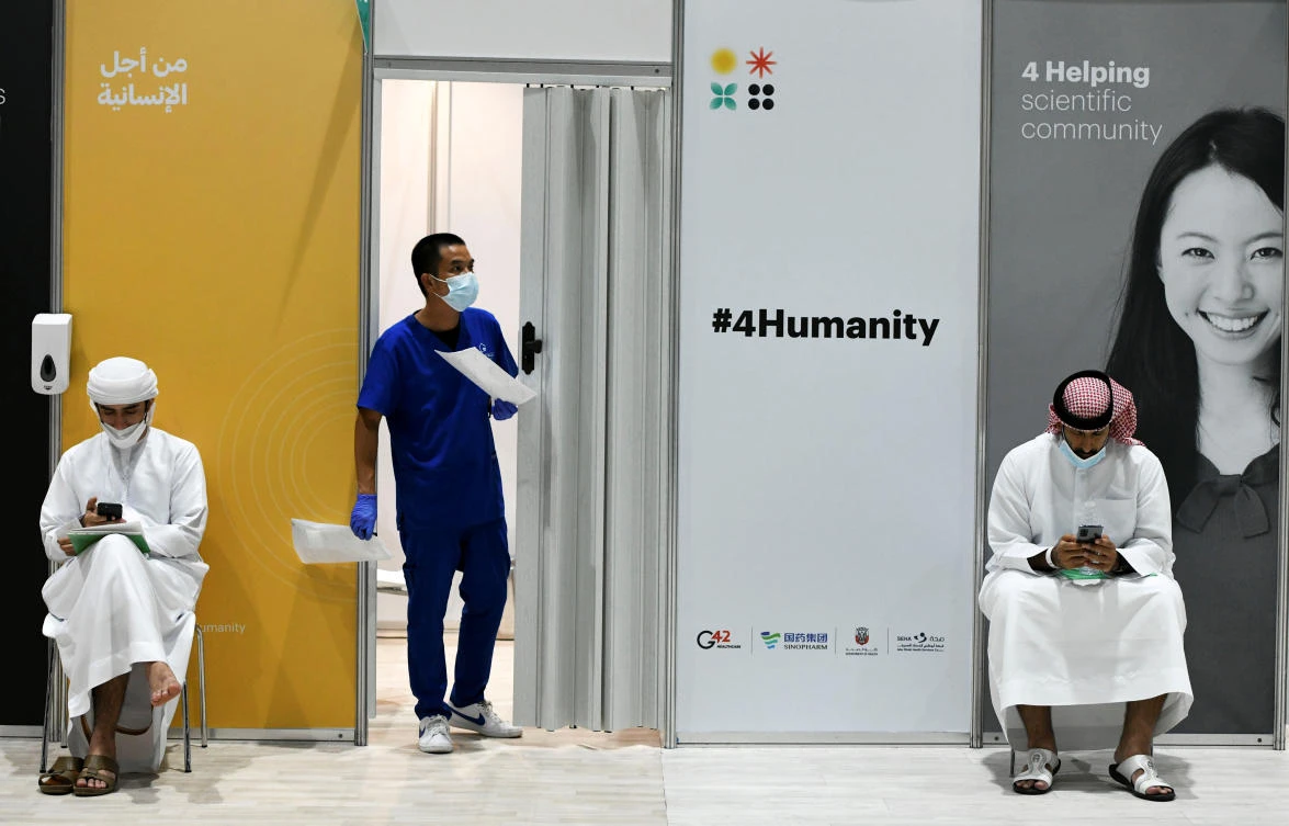 People wearing protective face masks use their mobiles as they wait for vaccine trials at Abu Dhabi National Exhibition Centre in Abu Dhabi, United Arab Emirates, October 6, 2020. Picture taken October 6, 2020. REUTERS/Khushnum Bhandari. NO RESALES. NO ARCHIVES.