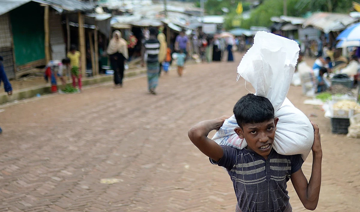 A Rohingya refugee youth carries relief materials at a refugee camp in Ukhia. (AFP)