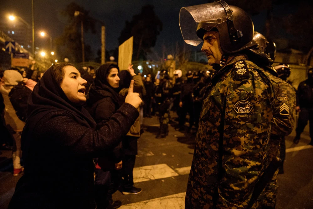 A woman attending a candlelight vigil, in memory of the victims of Ukraine International Airlines Boeing 737, talks to a policeman following the gathering in front of the Amirkabir University in the Iranian capital Tehran on Jan. 11, 2020. (Photo by Mona Hoobrhfker/ ISNA / AFP)