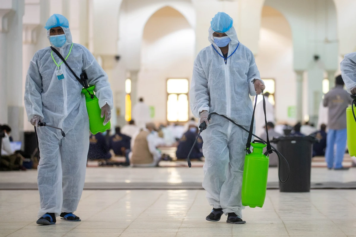 Health workers wearing personal protective equipment (PPE) disinfect the floor as Muslim pilgrims pray inside Namira Mosque in Arafat, outside the holy city of Makkah. (File/Reuters)
