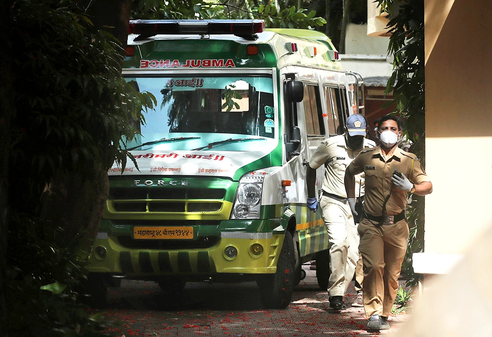 Policemen are seen on June 14 near an ambulance carrying the body of Bollywood actor Sushant Singh Rajput outside the building where he lived in Mumbai. (Files/AP)