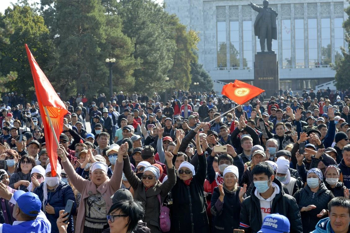 Protesters react waving Kyrgyz national flags as they wait for Kyrgyz Prime Minister Sadyr Zhaparov speech in front of the government building with a statue of Vladimir Lenin in the background in Bishkek, Kyrgyzstan, Wednesday, Oct. 14, 2020. (AP)