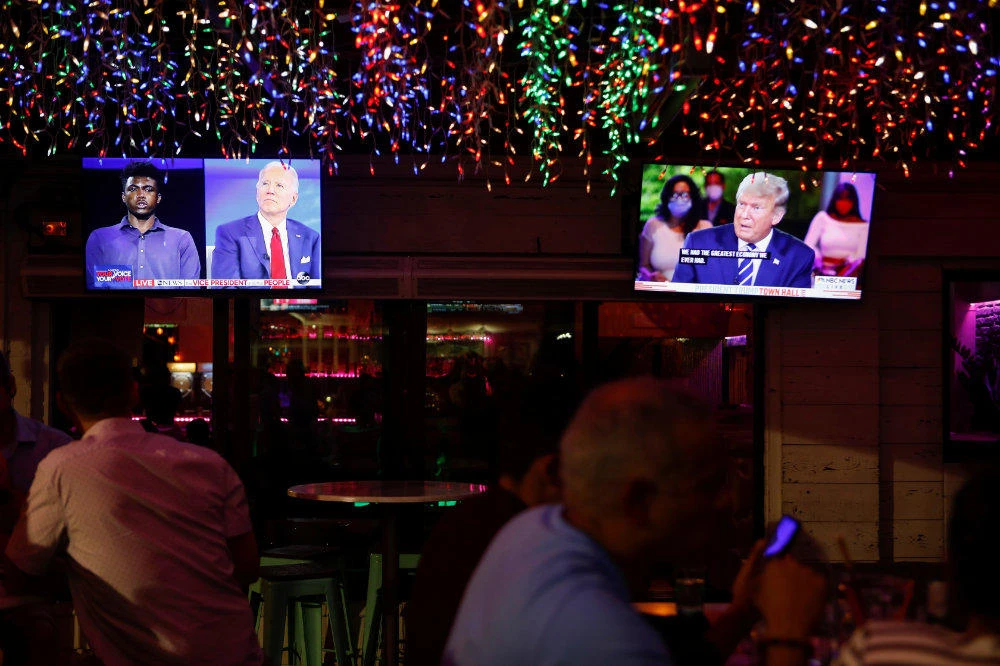 The dual town halls of US Democratic presidential candidate Joe Biden and President Donald Trump are seen on television monitors at Luv Child restaurant ahead of the election in Tampa, Florida, on October 15, 2020. (REUTERS/Octavio Jones)