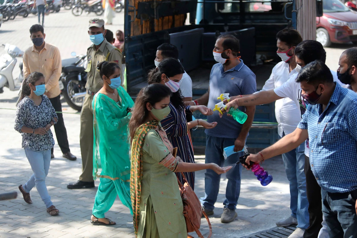 Volunteers offer hand sanitizers to devotee arriving at a temple dedicated to Hindu goddess Kali in Jammu, India, Saturday, Oct. 17, 2020. (AP)