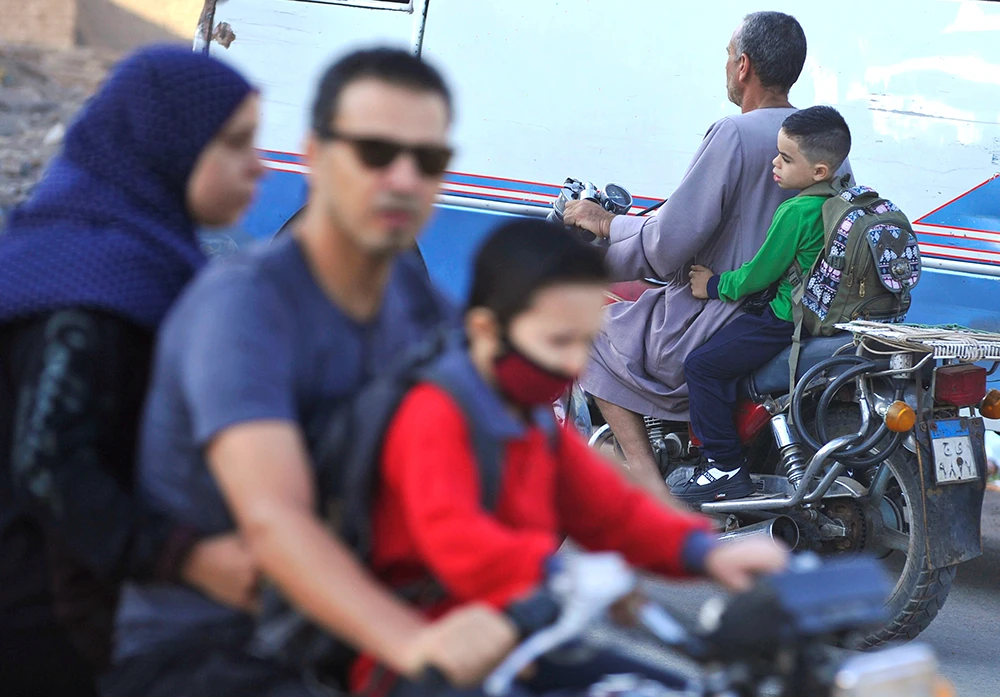 Students are being transported by their family members on motorcycles during the first day of school, following months of closure due to the coronavirus disease (COVID-19) outbreak in the Giza suburb of Awsim, Egypt October 18, 2020. (Reuters)