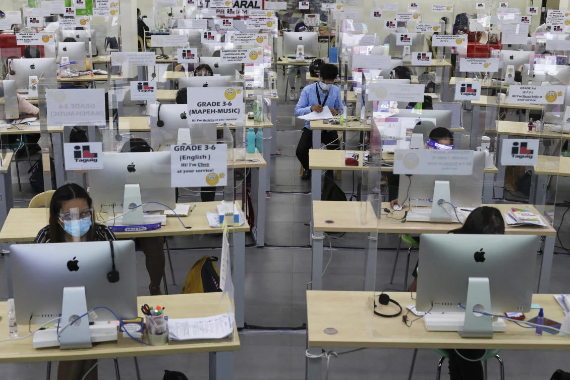 Teachers wear face masks and face shields while checking papers beside plastic barriers as they hold online classes on Monday, Oct. 19, 2020. (AP)