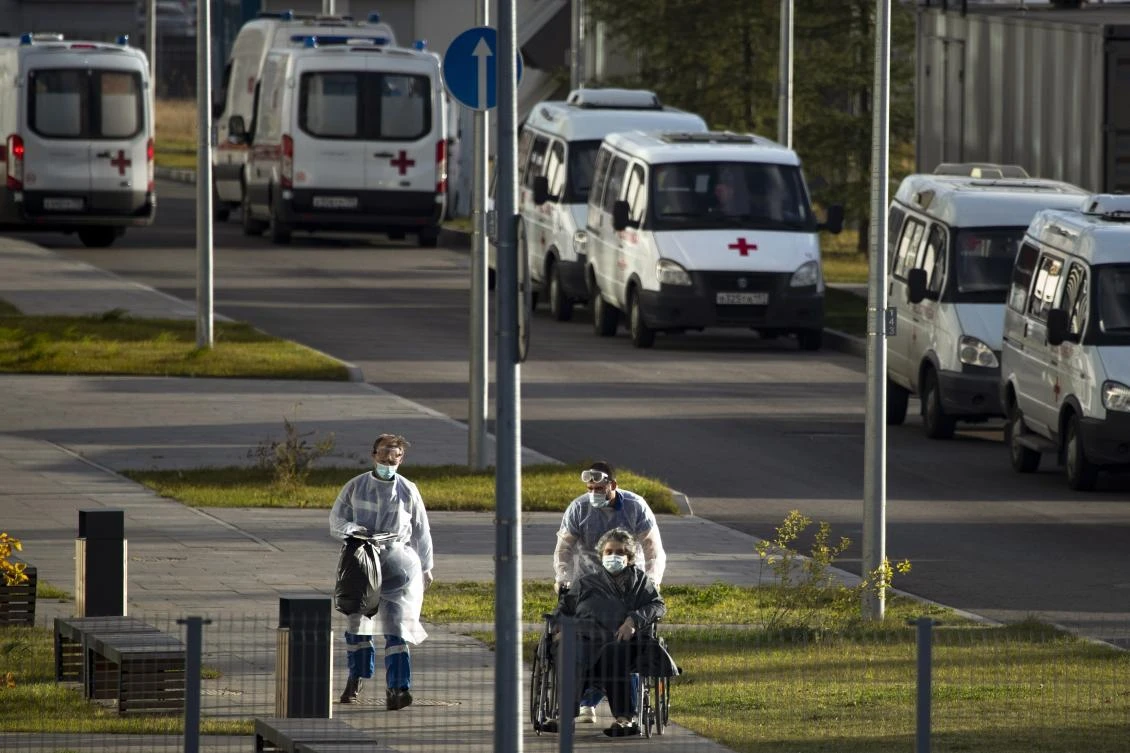 A medical worker wearing protective gear push a wheelchair with a patient suspected of having coronavirus at a hospital outside Moscow, Russia, Thursday, Oct. 15, 2020. Life outside hospitals remains largely normal. Moscow officials recommended the elderly and those who have chronic illnesses stay home. (AP)