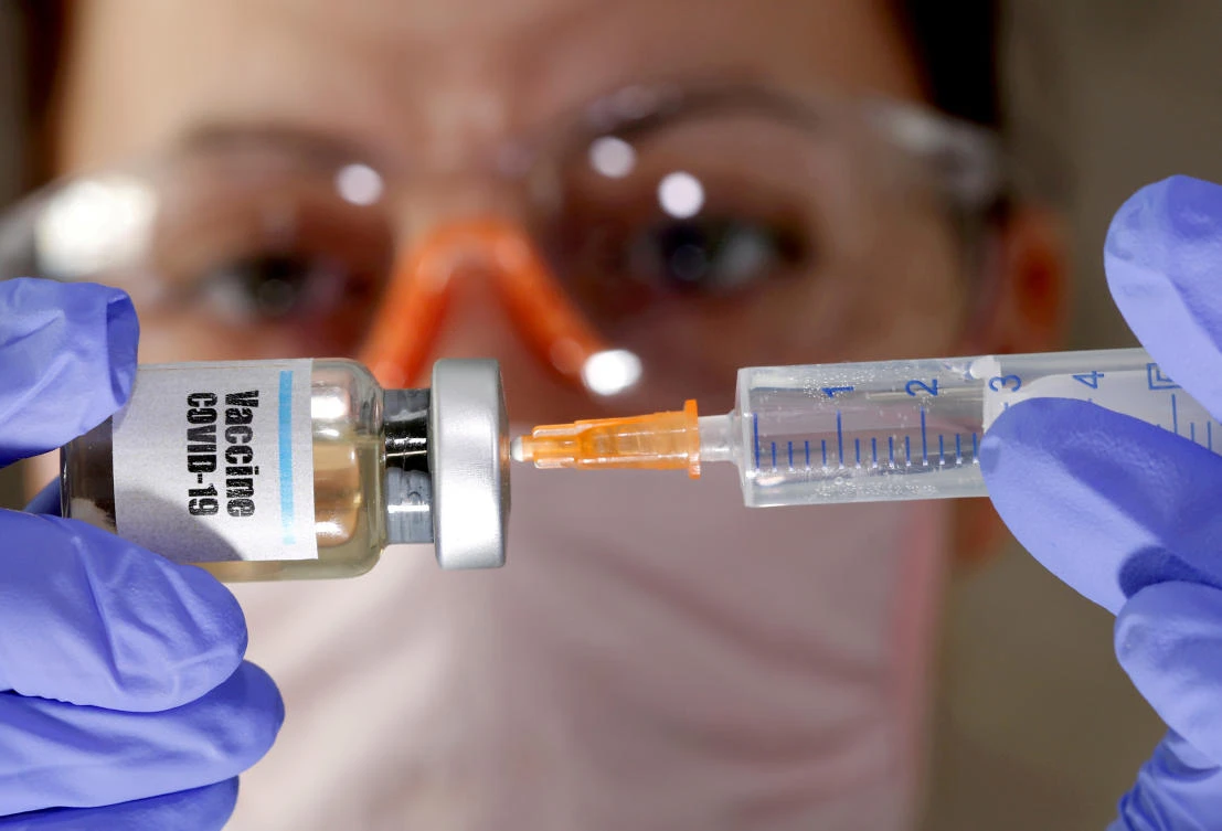 A woman holds a small bottle labeled with a "Vaccine COVID-19" sticker and a medical syringe in this illustration taken April 10, 2020. (Reuters)