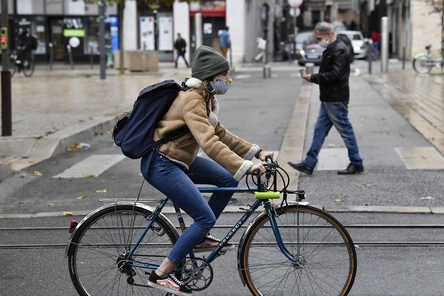 A woman wearing a protective face mask as a measure against the spread of the Covid-19 (novel coronavirus) pandemic, rides a bicycle on October 22, 2020 in a street of Saint-Etienne, central eastern France. (File/AFP)