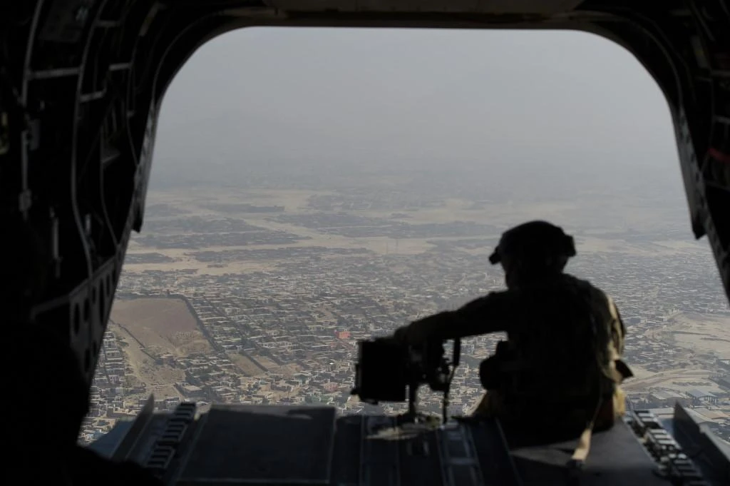 Above, a US serviceman aboard a Chinook helicopter in Afghanistan. A US air strike in Wardak province on Sunday evening targeted Taliban fighters, killing five. (AFP file photo)