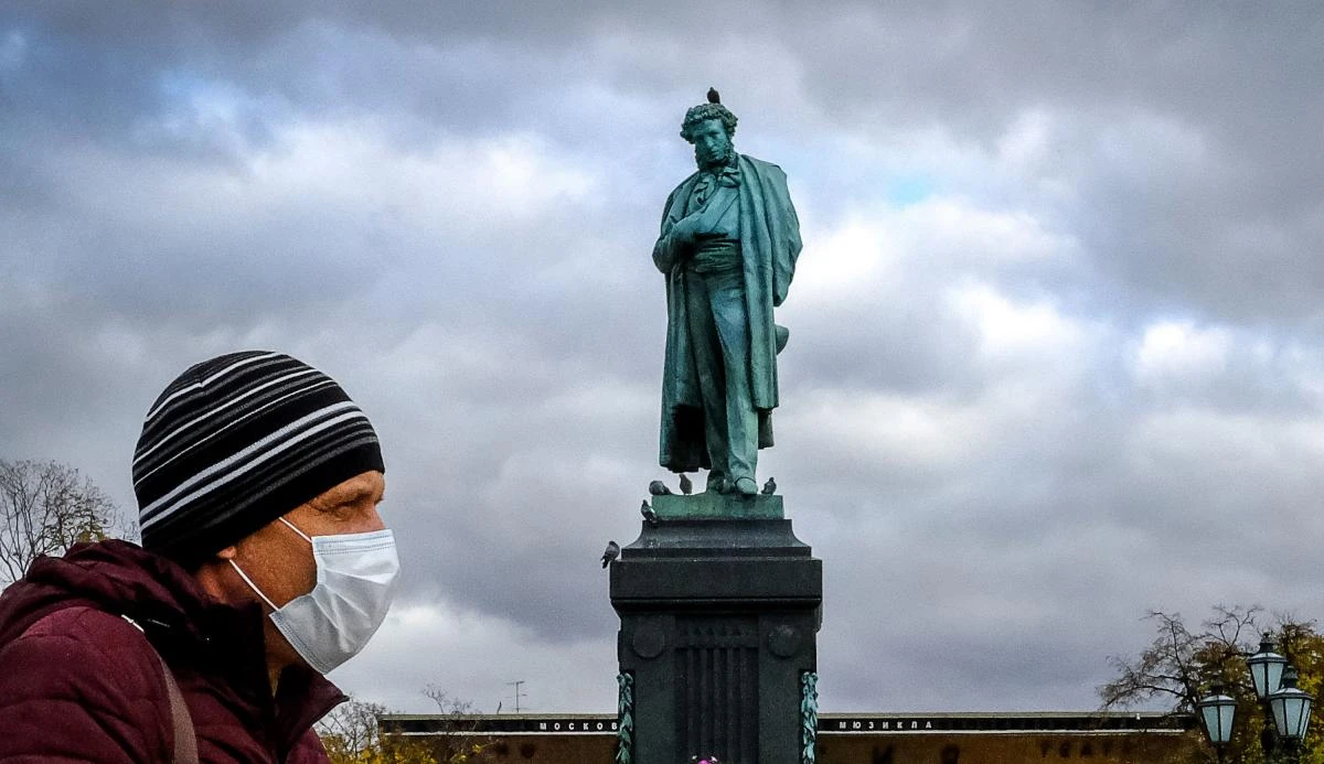 A man wearing a face mask to protect against the coronavirus disease walks past a monument to Russian poet Alexander Pushkin in central Moscow on October 26, 2020. (AFP)