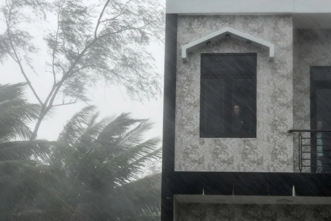 A man looks out a window as strong winds batter central Vietnam's Quang Ngai province on October 28, 2020, as Typhoon Molave makes landfall. (AFP)