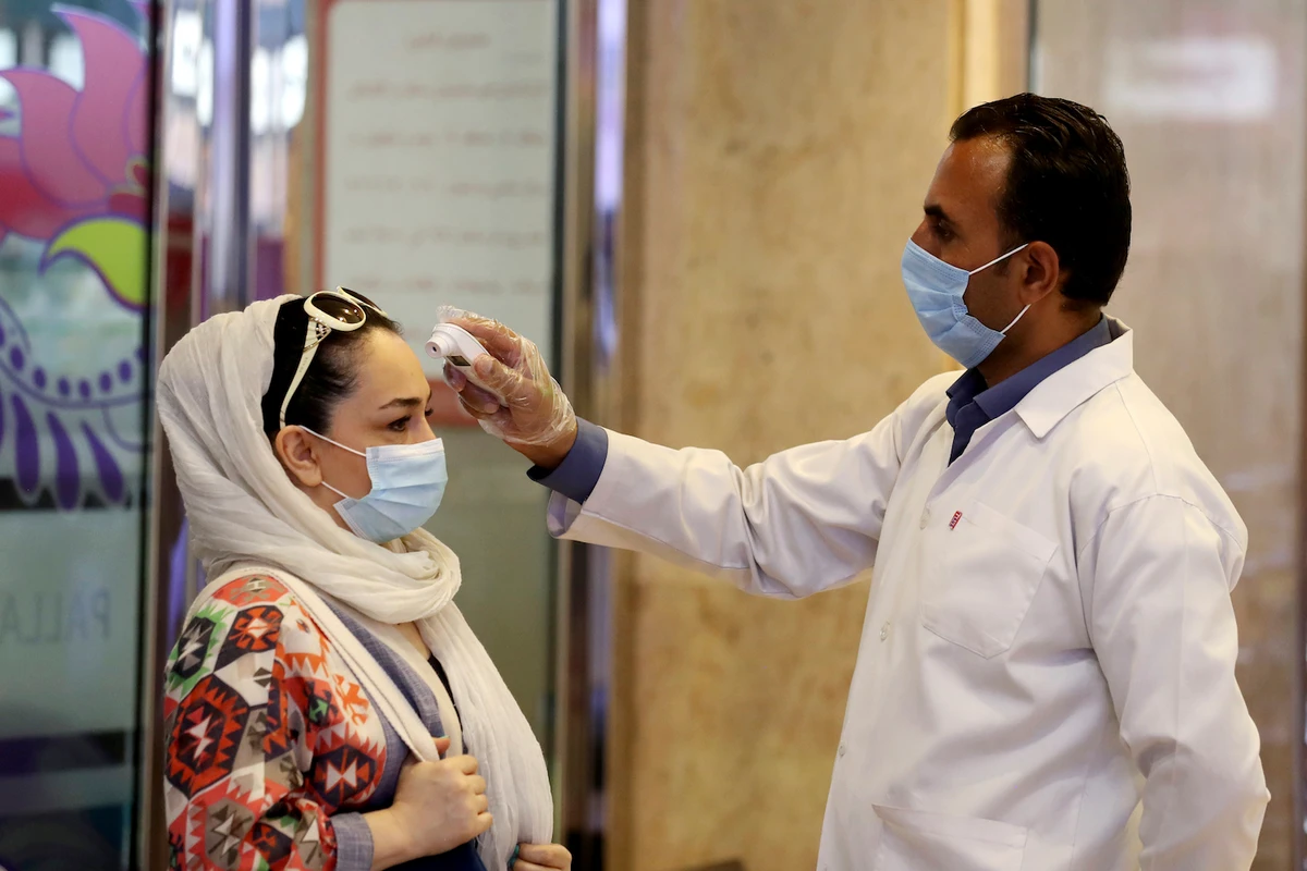 A woman wearing a protective face mask to help prevent spread of the coronavirus has her temperature checked as she enters a shopping center, in Tehran, Iran. (File/AP)