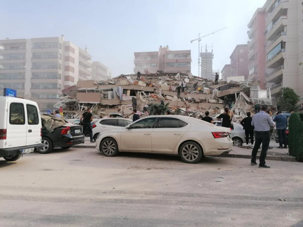People look at a collapsed house in an earthquake-hit area of Izmir, on October 30, 2020 after major 7.0 magnitude earthquake struck off the coast of western Turkey. The USGS said the quake was registered 14 kilometres (8.6 miles) off the Greek town of Neon Karlovasion on the Aegean Sea island of Samos. (AFP/Demiroren News Agency)