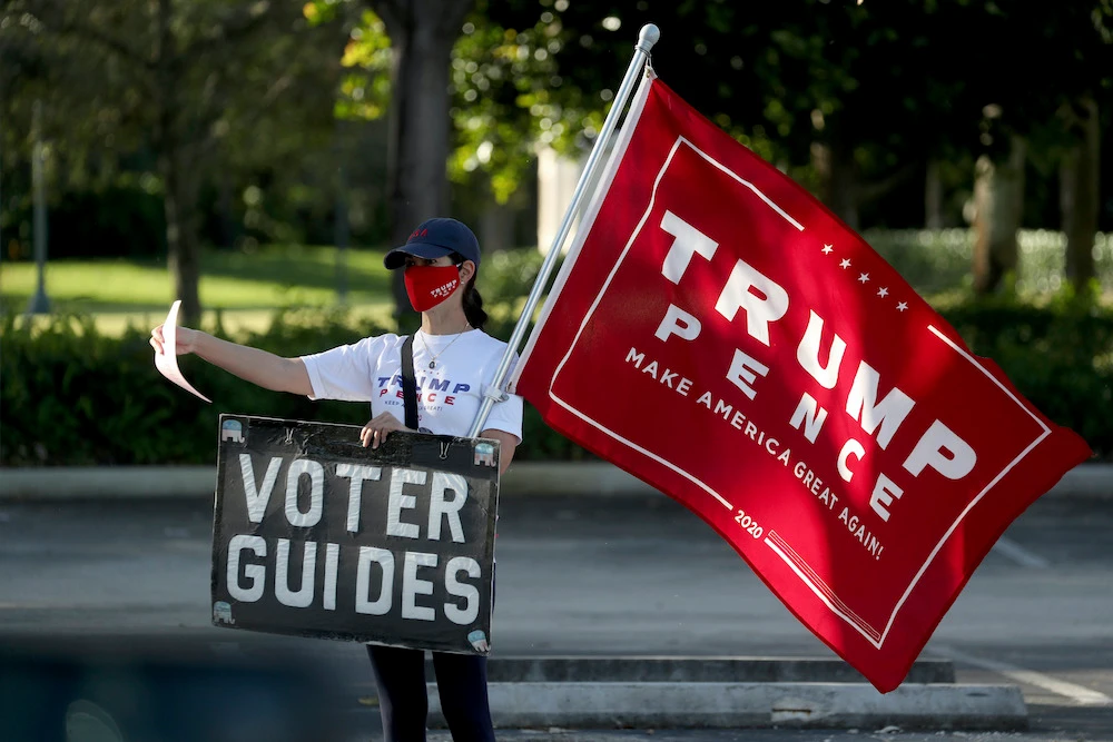 A Trump supporter campaigns on Election Day at the Weston Branch Library on Tuesday Nov. 3, 2020, in Weston, Florida. (South Florida Sun-Sentinel via AP)