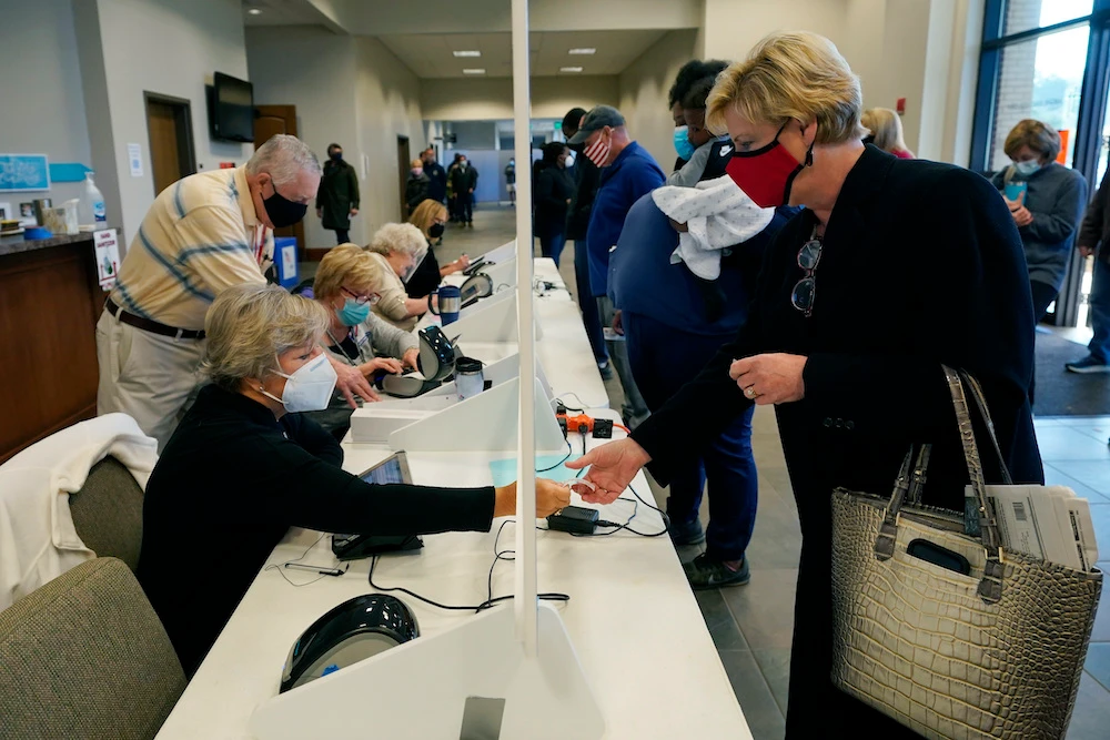 Masked election workers sit behind a clear barrier as they perform ID checks of potential voters on Election Day, in Ridgeland, Mississippi, Tuesday, Nov. 3, 2020. (AP)