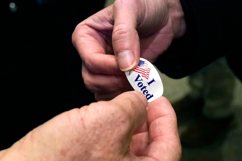Election worker Bubba Wright, left, hands out “I Voted” stickers to voters on Election Day as they leave a Ridgeland, Mississippi, precinct Tuesday, Nov. 3, 2020. (AP)