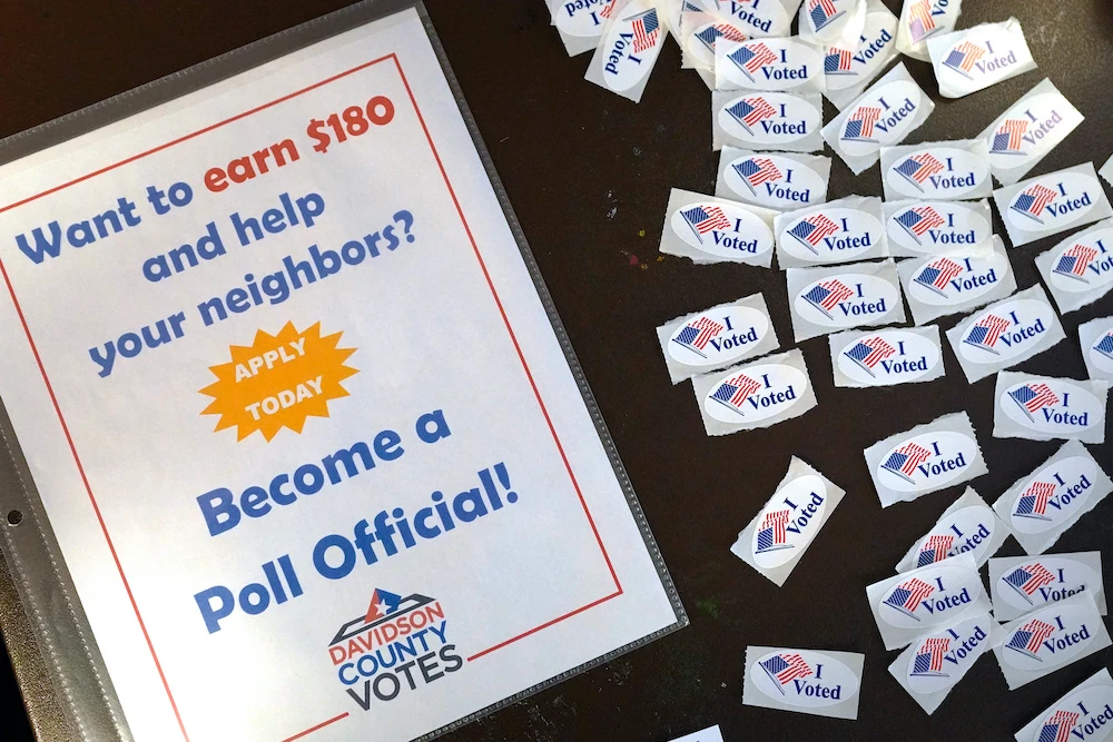 A sign calling for voters to work at voting locations is displayed on a table along with voting stickers at the Bordeaux Library voting precinct on Election Day Tuesday, Nov. 3, 2020, in Nashville, Tennessee. (AP)