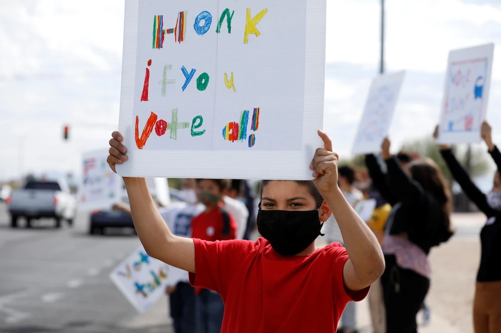 Students from South Side Community elementary school display signs encouraging motorists to vote on the afternoon of the presidential election in South Tucson, Arizona, US Nov. 3, 2020. (Reuters)