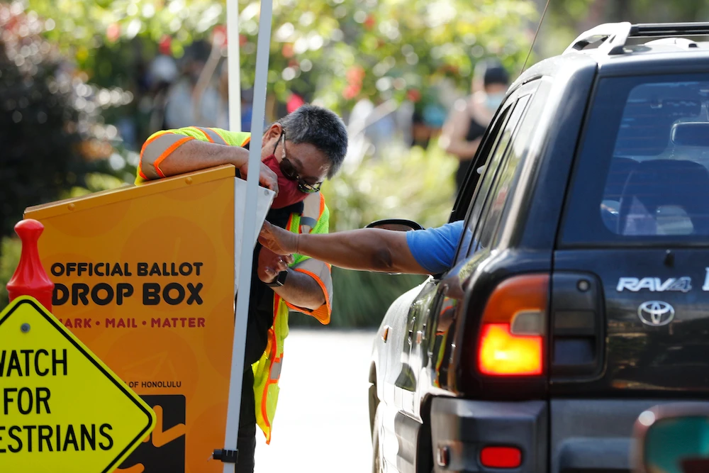An attendant helps a driver drop off a ballot on Election Day, Tuesday, Nov. 3, 2020, in Honolulu. (AP)
