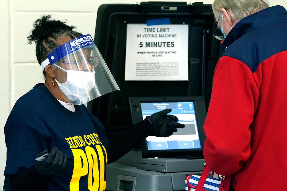 Precinct 36 poll worker Vivian Bibens is decked out in her personal protective equipement as she explains the purpose of the ballot scanner to a voter on Election Day in Jackson, Mississippi, Tuesday, Nov. 3, 2020. (AP)