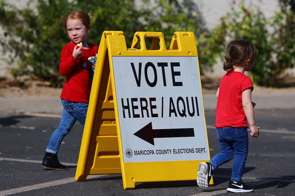 Children walk past a voting direction sign during the 2020 presidential election in Avondale, Arizona, US, Nov. 3, 2020. (Reuters)