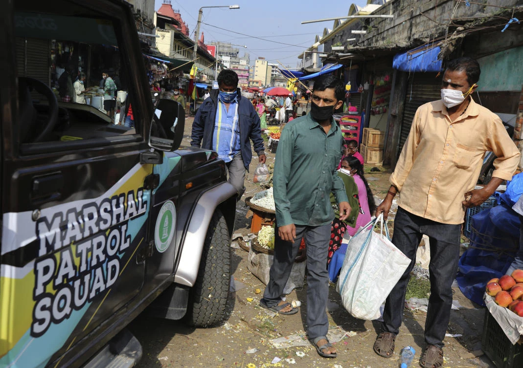 Shoppers wearing face masks as a precaution against the coronavirus watch a vehicle carrying municipal officers looking for offenders flouting compulsory rules for face masks in public, at a market in Bengaluru, India, Thursday, Oct. 29, 2020. (AP)