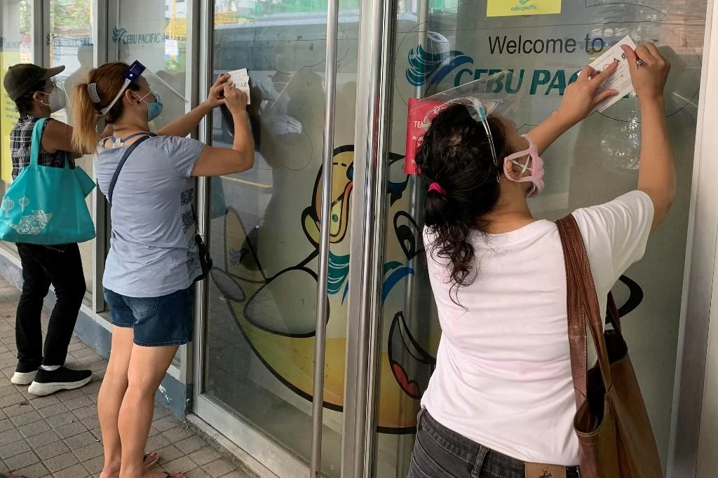Shoppers wearing face shields fill up forms before being allowed inside a grocery store in Manila, as part of coronavirus health protocols imposed by Philippine authorities. (AFP file photo)