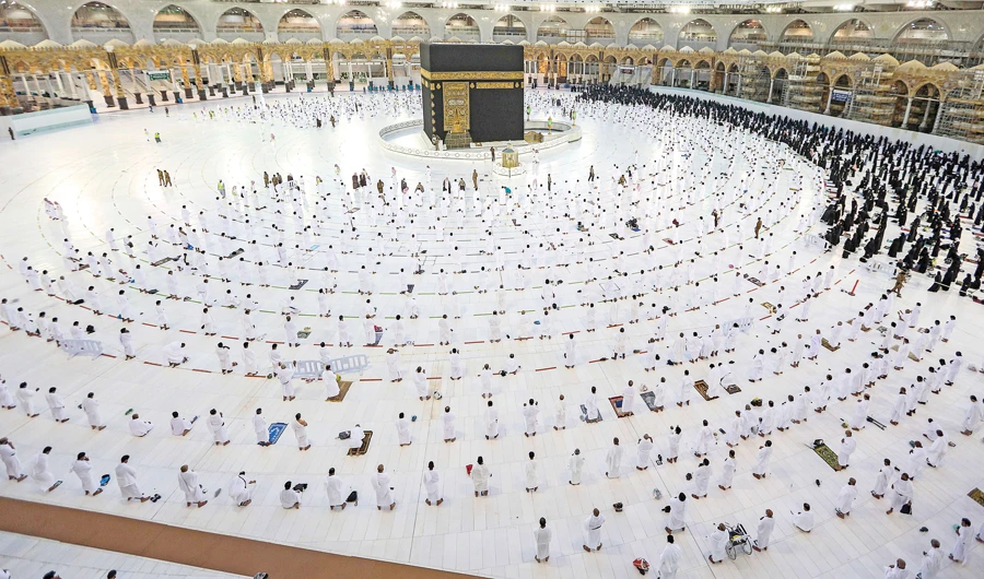 Umrah pilgrims, keeping a safe social distance, offer prayers in the Grand Mosque in Makkah. Saudi Arabia is gradually lifting restrictions imposed following the outbreak of the coronavirus pandemic. (Reuters)