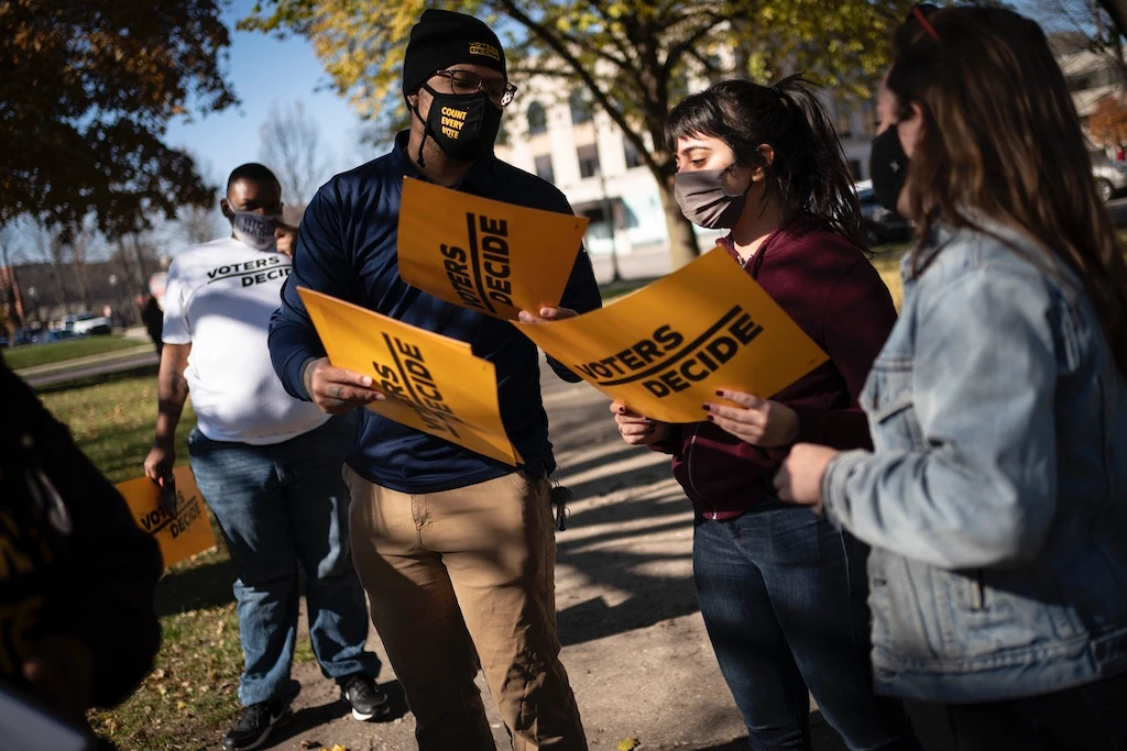 People gather with signs that read "Voters Decide" at the Civic Center Park while waiting for the results of election, Wednesday, Nov. 4, 2020, in Kenosha, Wis. (AP)